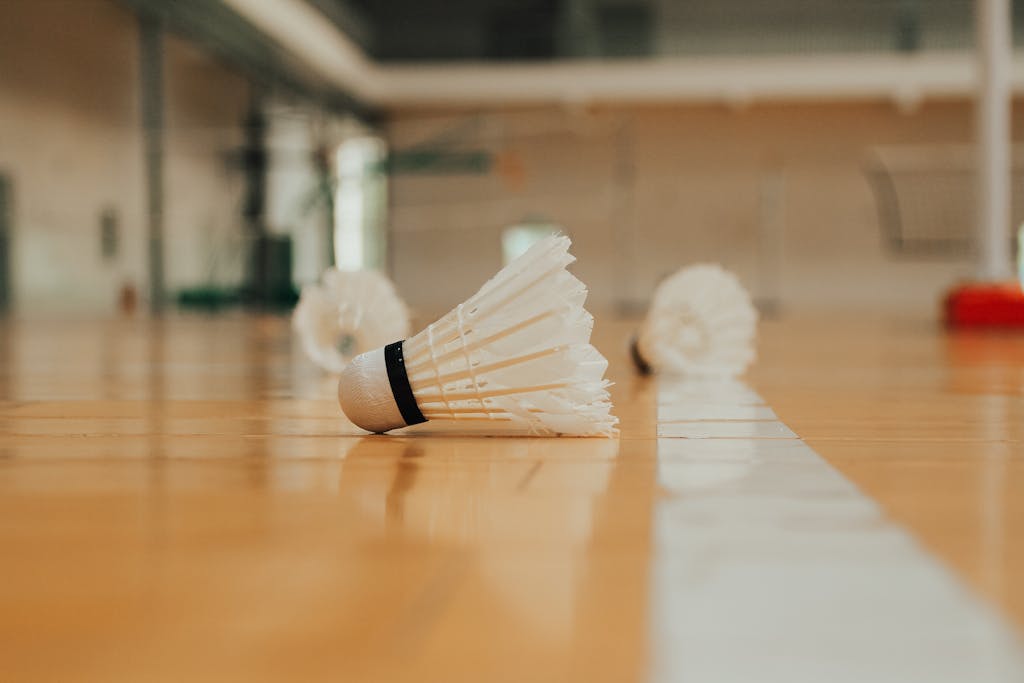 Photography taken at ground level of plastic shuttlecocks hardwood floor with white line marking